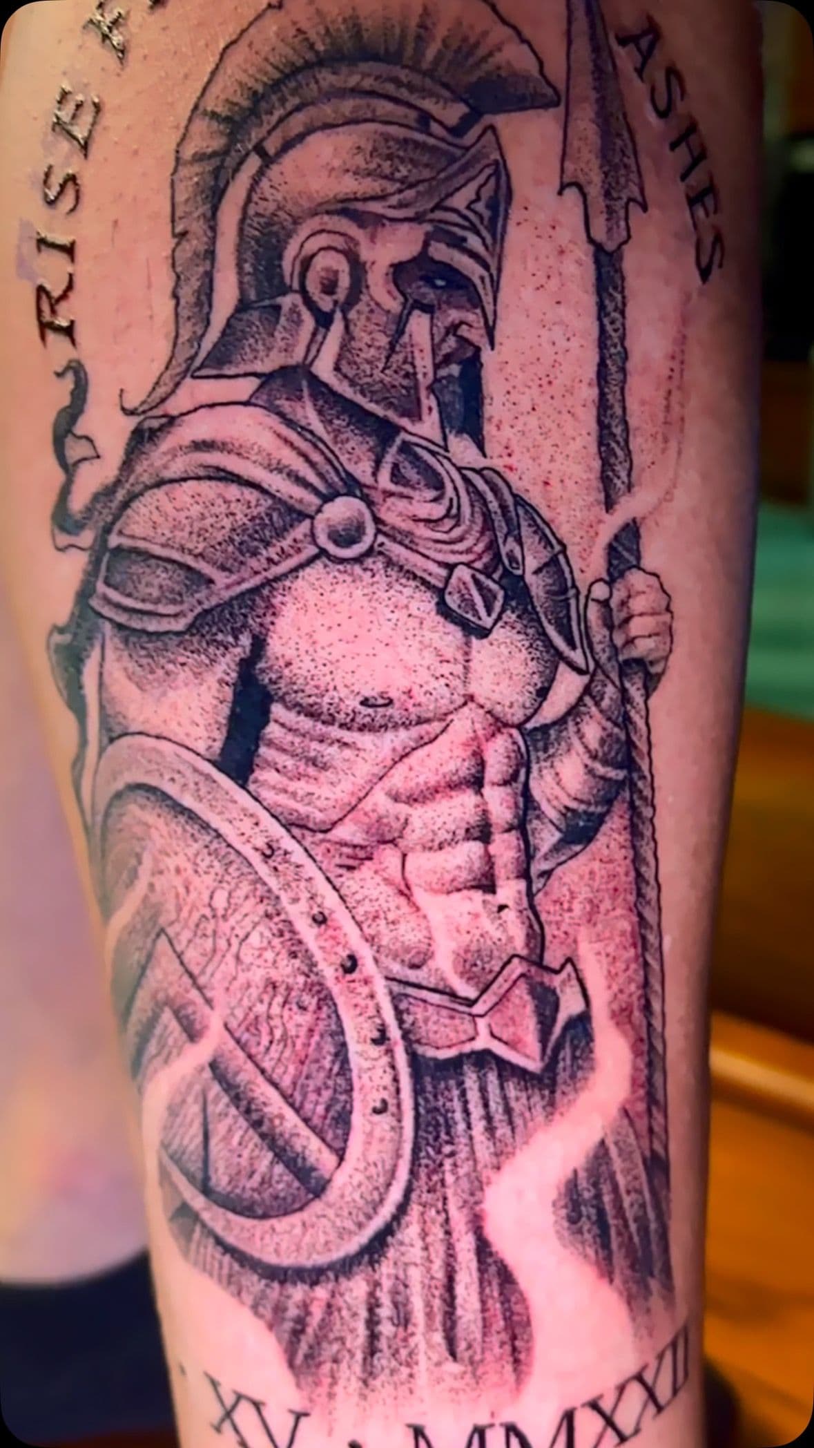 Black and grey illustrative Spartan warrior tattoo on upper arm