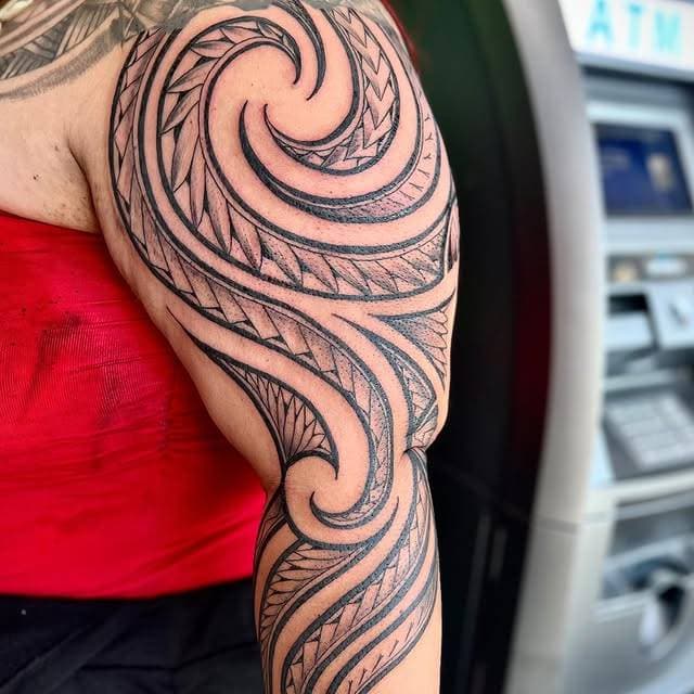 Blackwork tribal swirl tattoo on upper arm