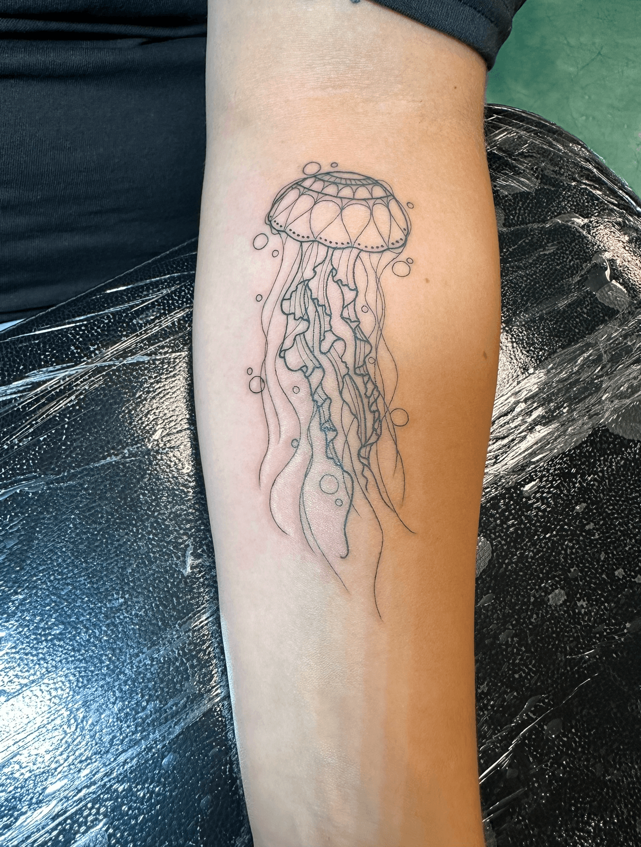 Black and grey fine line illustrative jellyfish tattoo on forearm