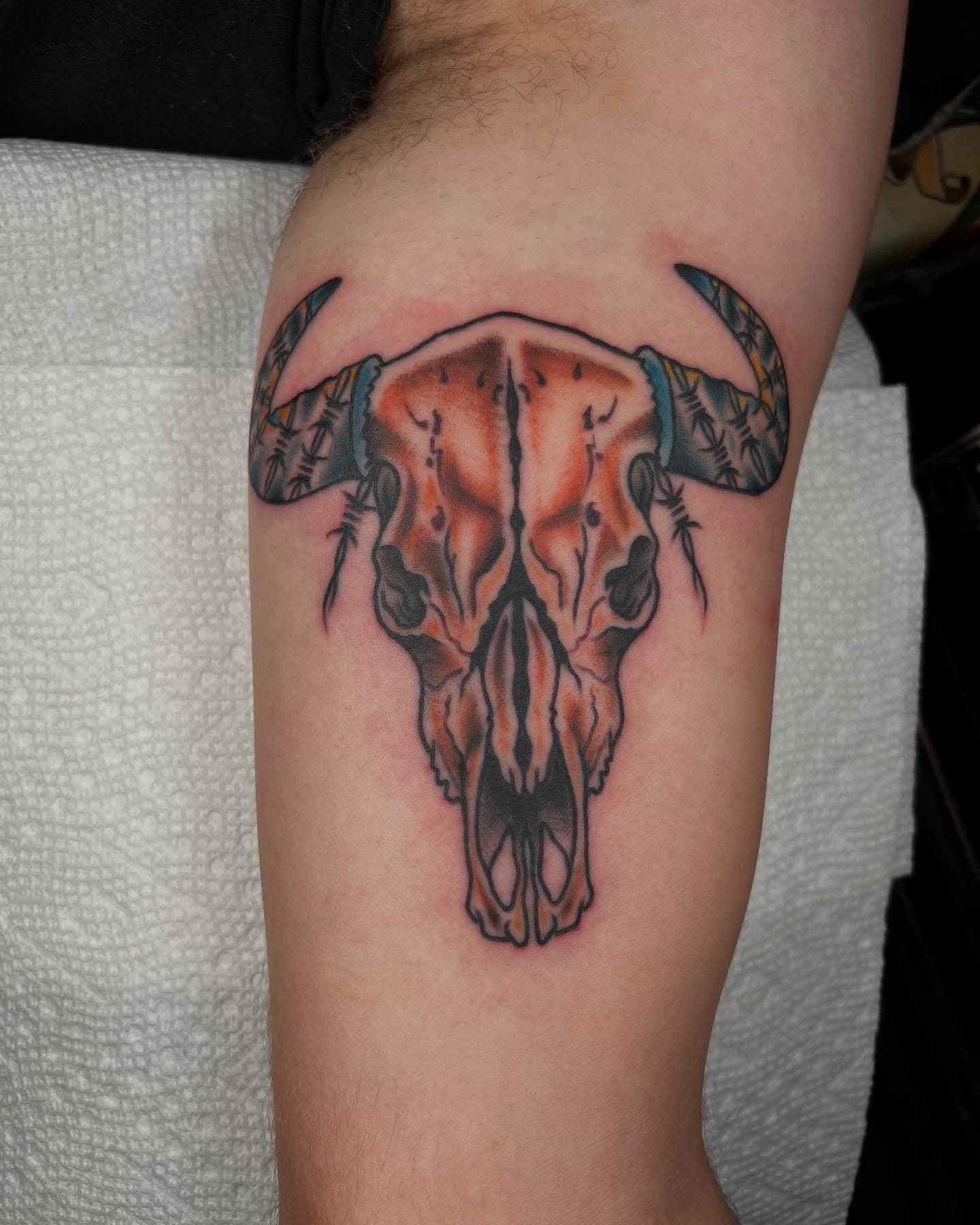 Colorful bull skull tattoo on upper arm.