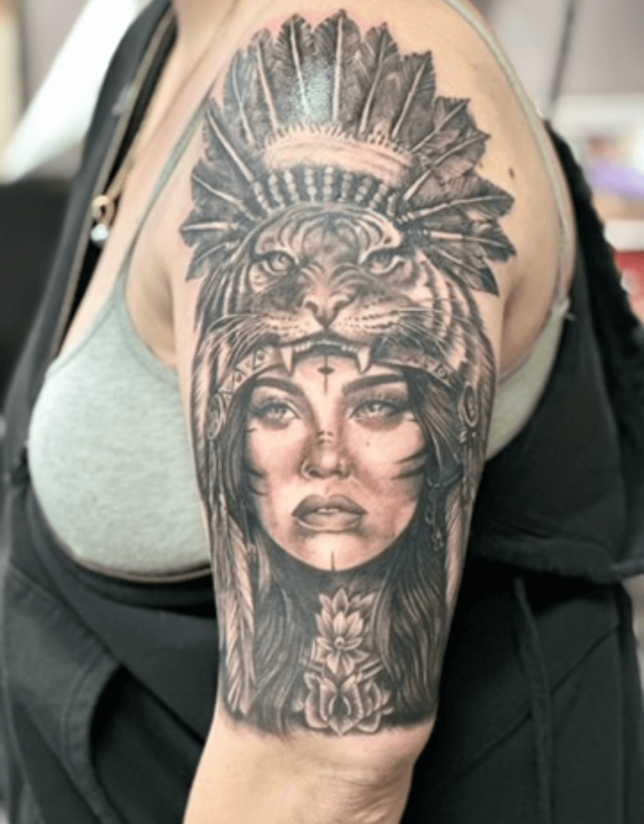Black and grey realistic portrait and headdress tattoo on upper arm