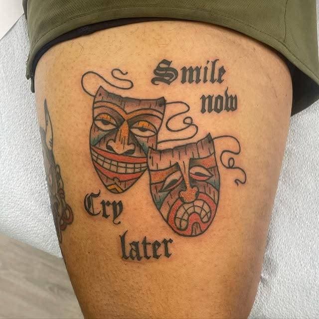 Colorful theater masks with 'Smile now Cry later' script on thigh