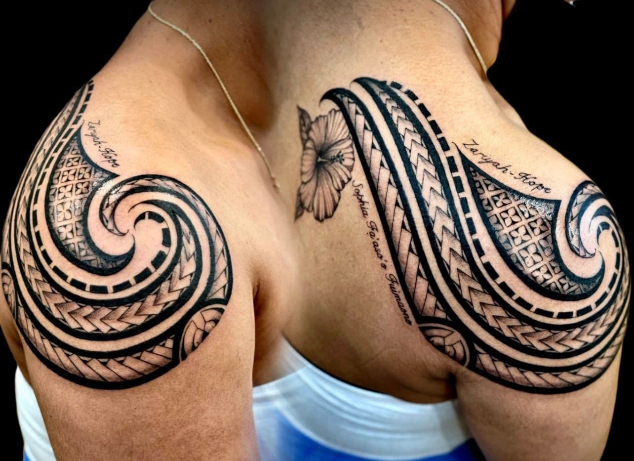 Black and grey tribal tattoo with lettering on shoulder